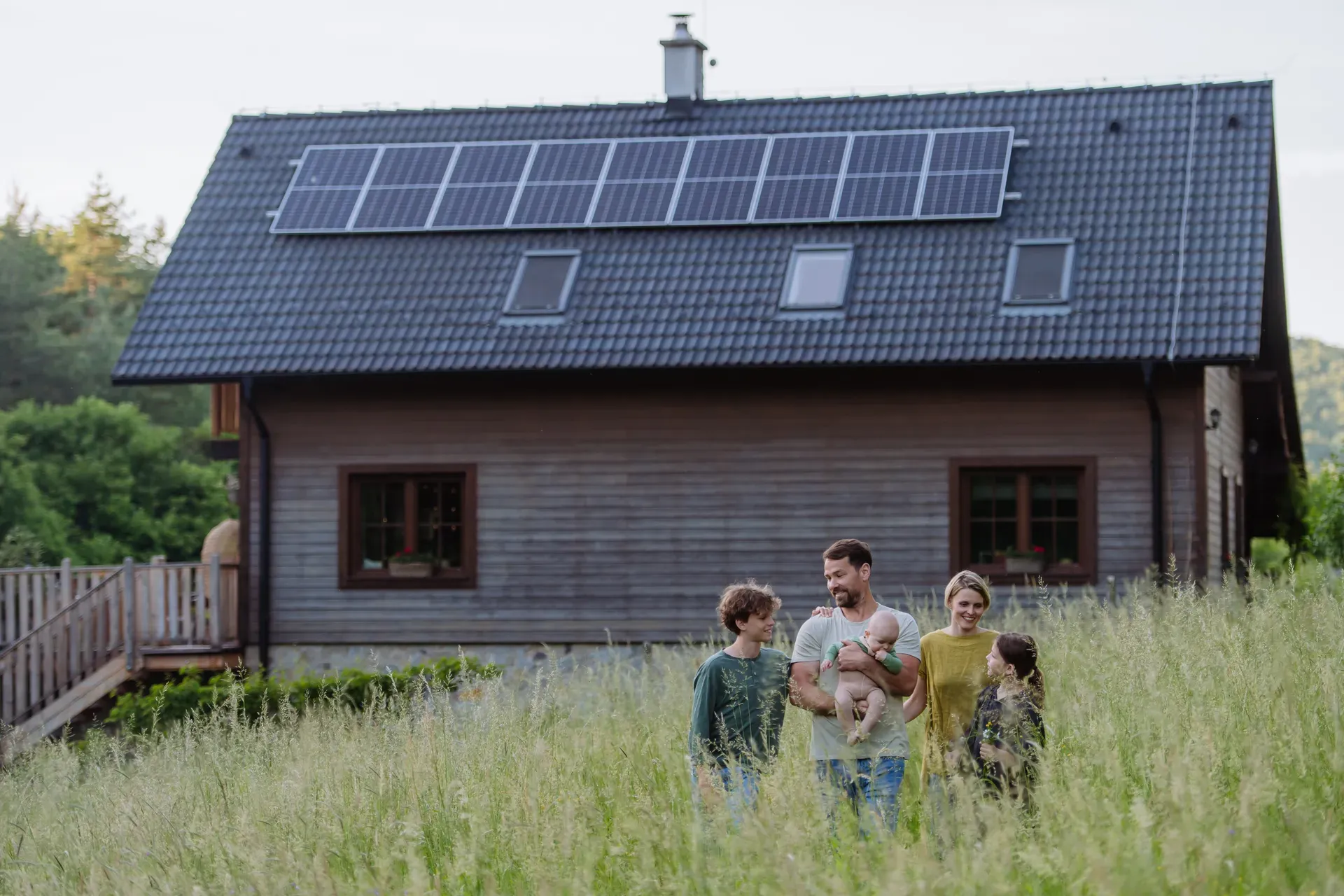 Famille heureuse près de leur maison avec des panneaux solaires